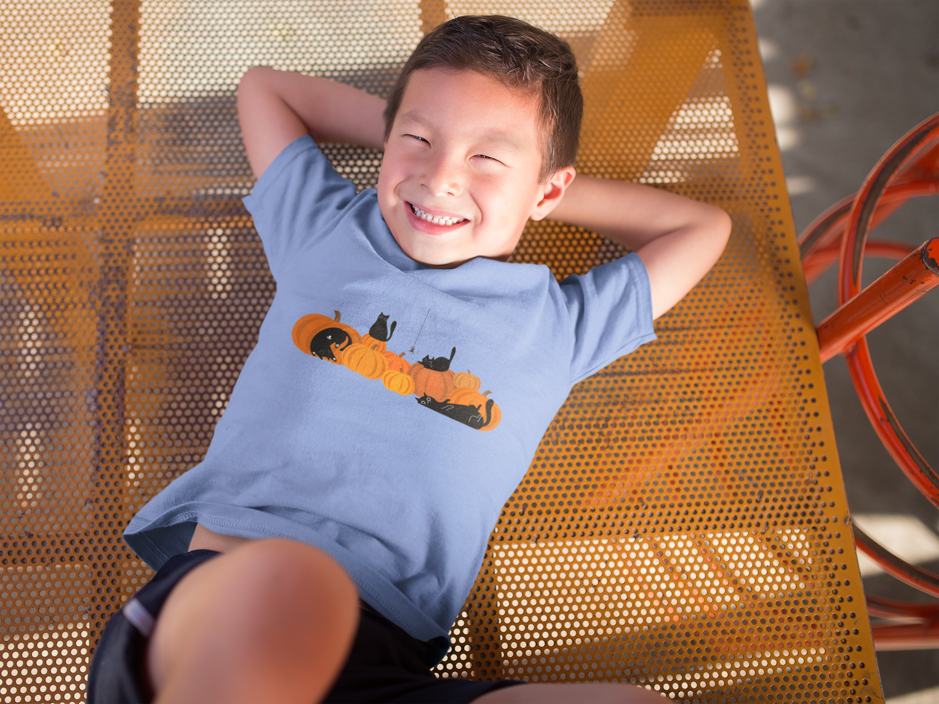 boy wearing a light blue halloween shirt that has pumpkins and black cats