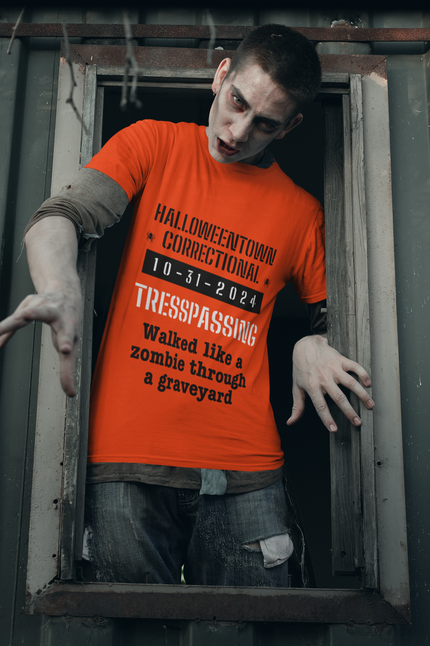 man dressed like a zombie wearing a shirt that says halloweentown correctional tresspassing walked like a zombie through a graveyard