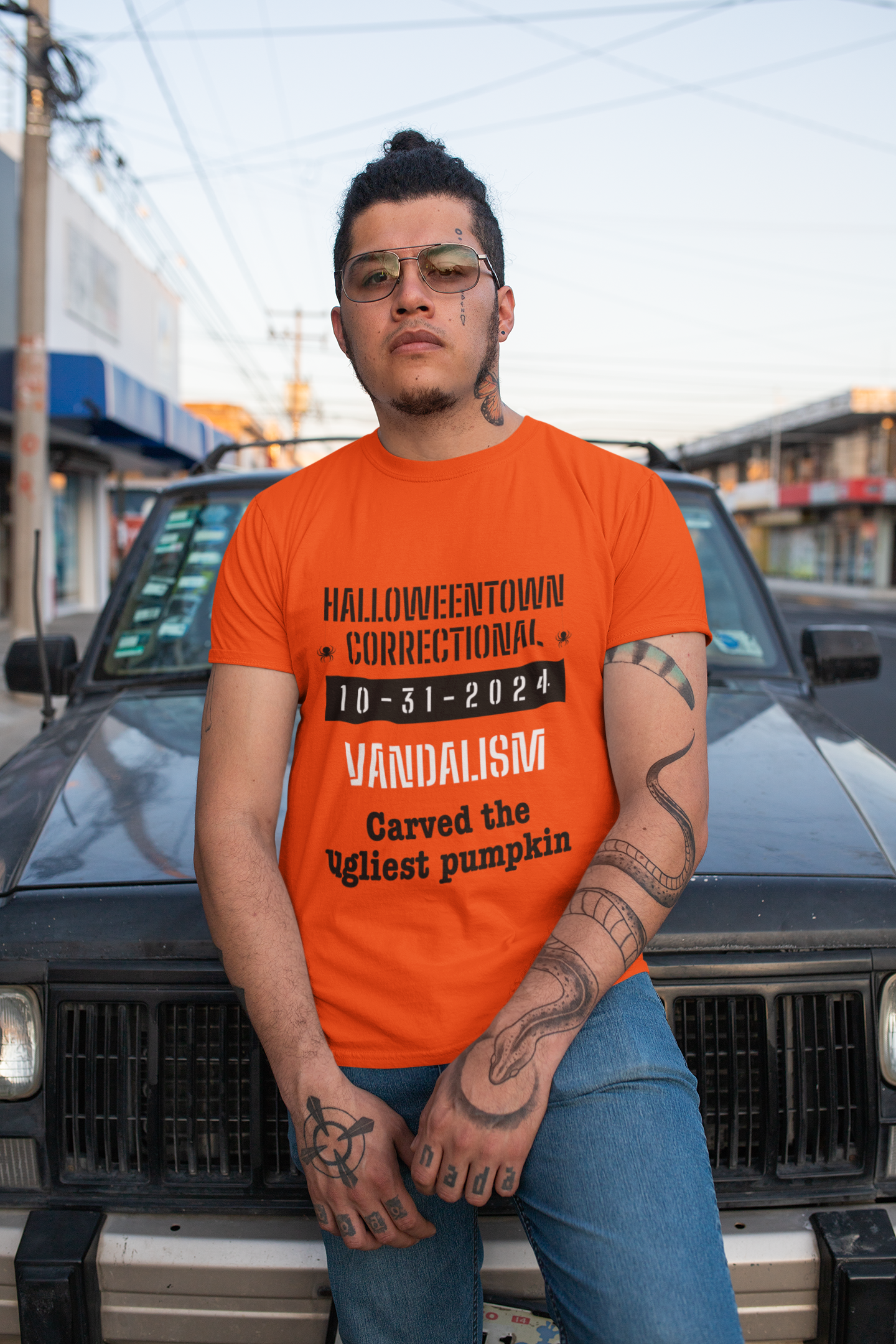 man wearing a shirt that says halloweentown correctional vandalism carved the uglist pumpkin