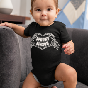 baby wearing a black onesie with skeleton hands making a heart that says spooky season inside halloween