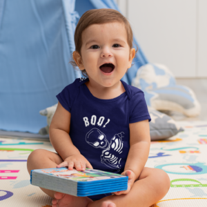 baby wearing a onesie with a skeleton playing peek a boo