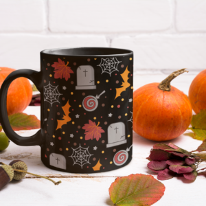 black mug with halloween pattern that has graves, candy, bats, and webs
